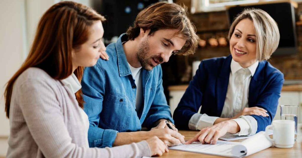 couple signing policy papers with a life insurance agent